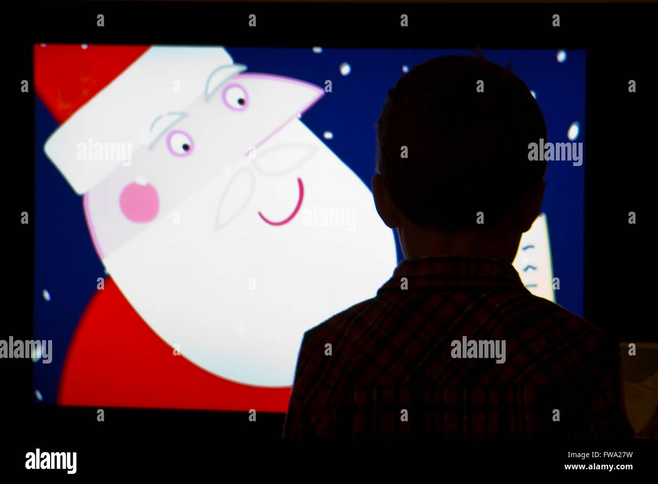 Silhouette of a three year old boy watching a television programme at Christmas Stock Photo