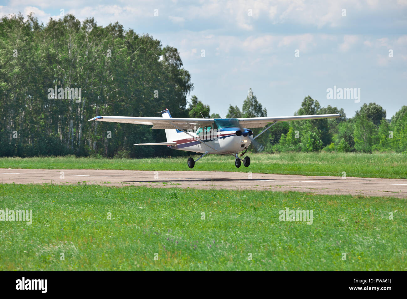 Light private plane landing on the runway of the airfield Stock Photo
