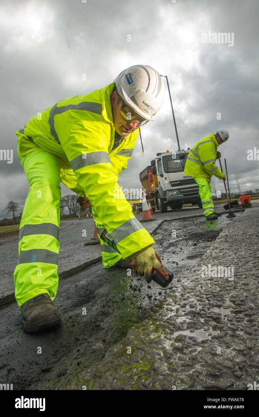 Road workers marking out faults on tarmac Stock Photo