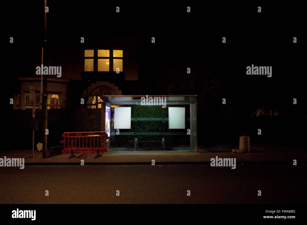 An empty bus stop in Belgium at night, lit by artificial street light. Stock Photo