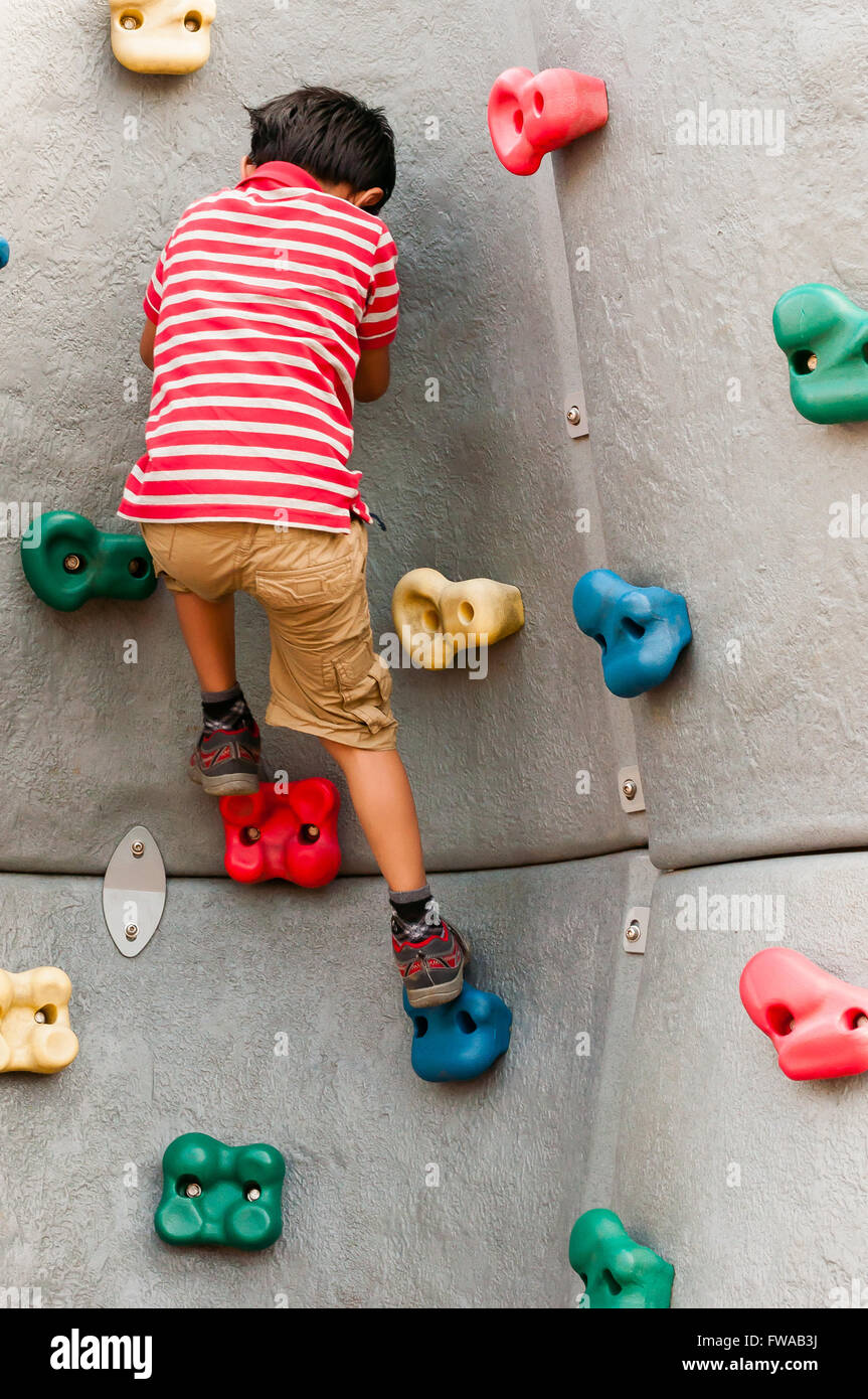 Toddler boy playing rock climbing during summer Stock Photo