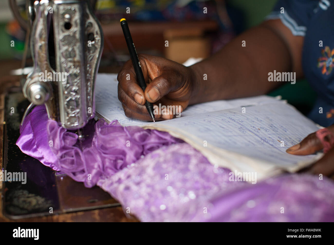 A female dressmaker doing some book keeping, Nigeria, Africa Stock Photo
