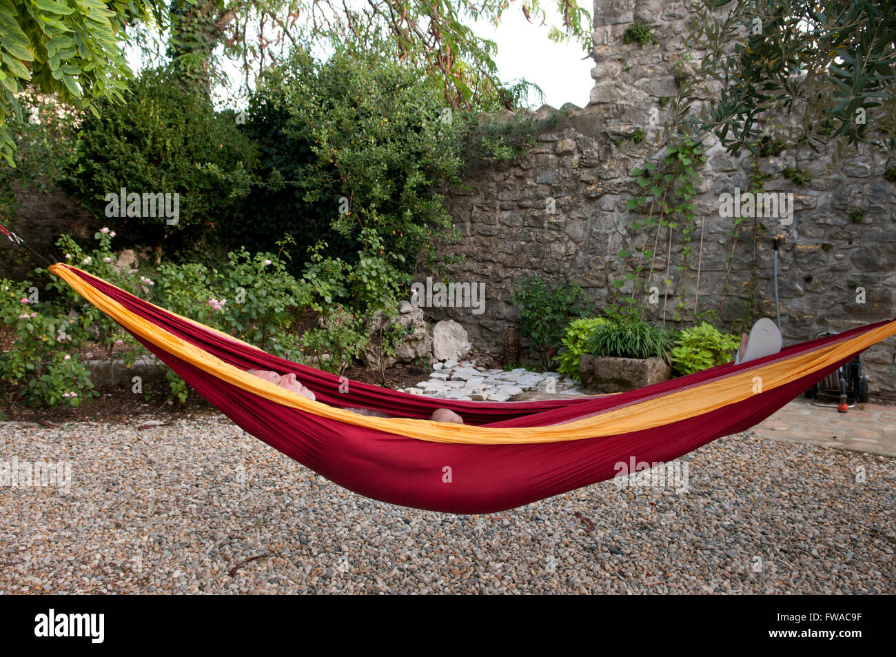 Mature man lying in a red and yellow hammock asleep Stock Photo