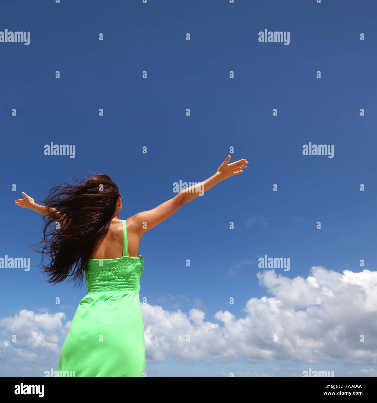 Woman with raised hands over blue sky background Stock Photo - Alamy