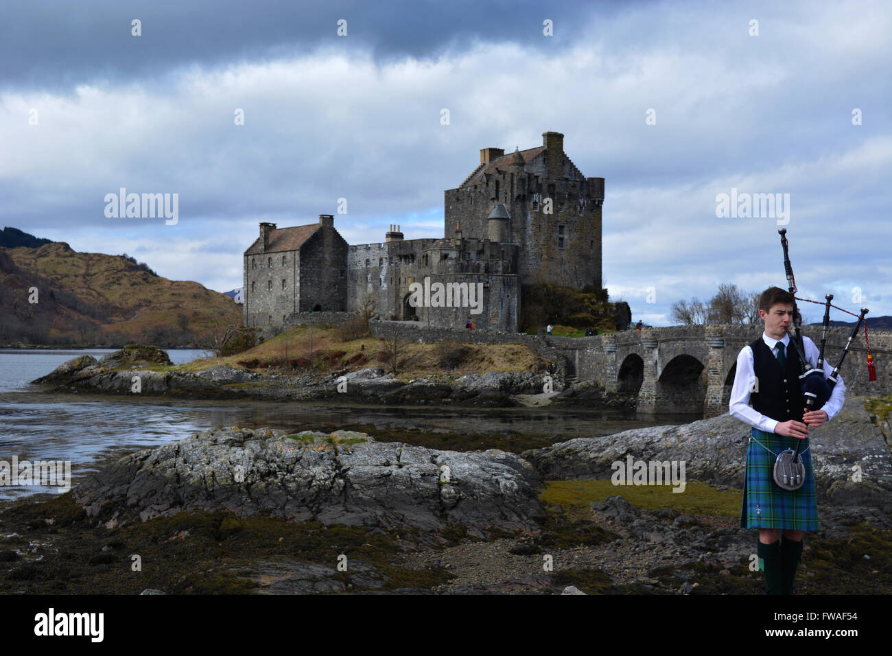 Traditional bagpiper with beautiful ancient castle in the Scottish ...
