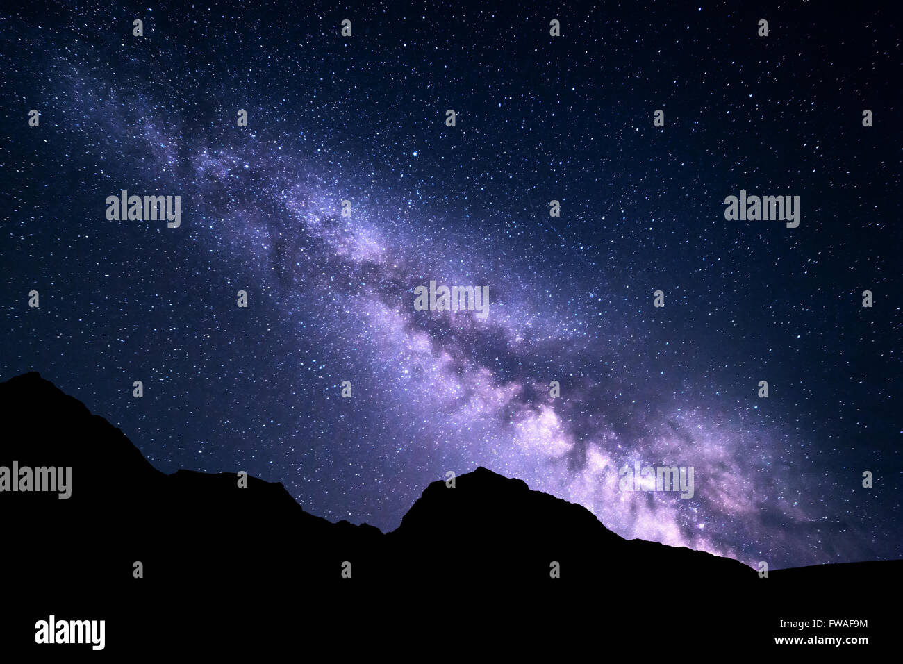 Mountain landscape with purple Milky Way. Beautiful night sky with stars and rocks at summer. Universe Stock Photo