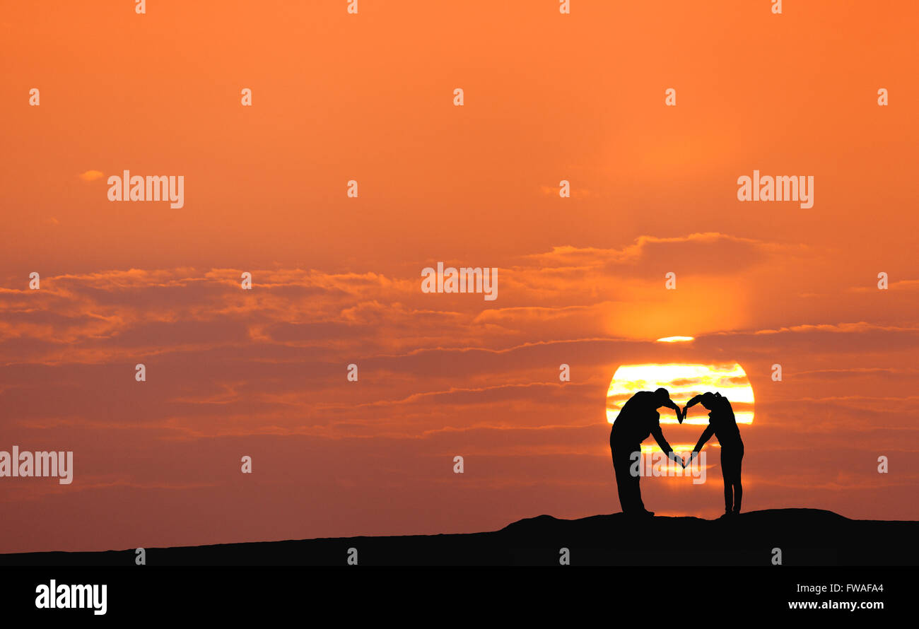 Sunset landscape with silhouette of man and woman holding hands in ...