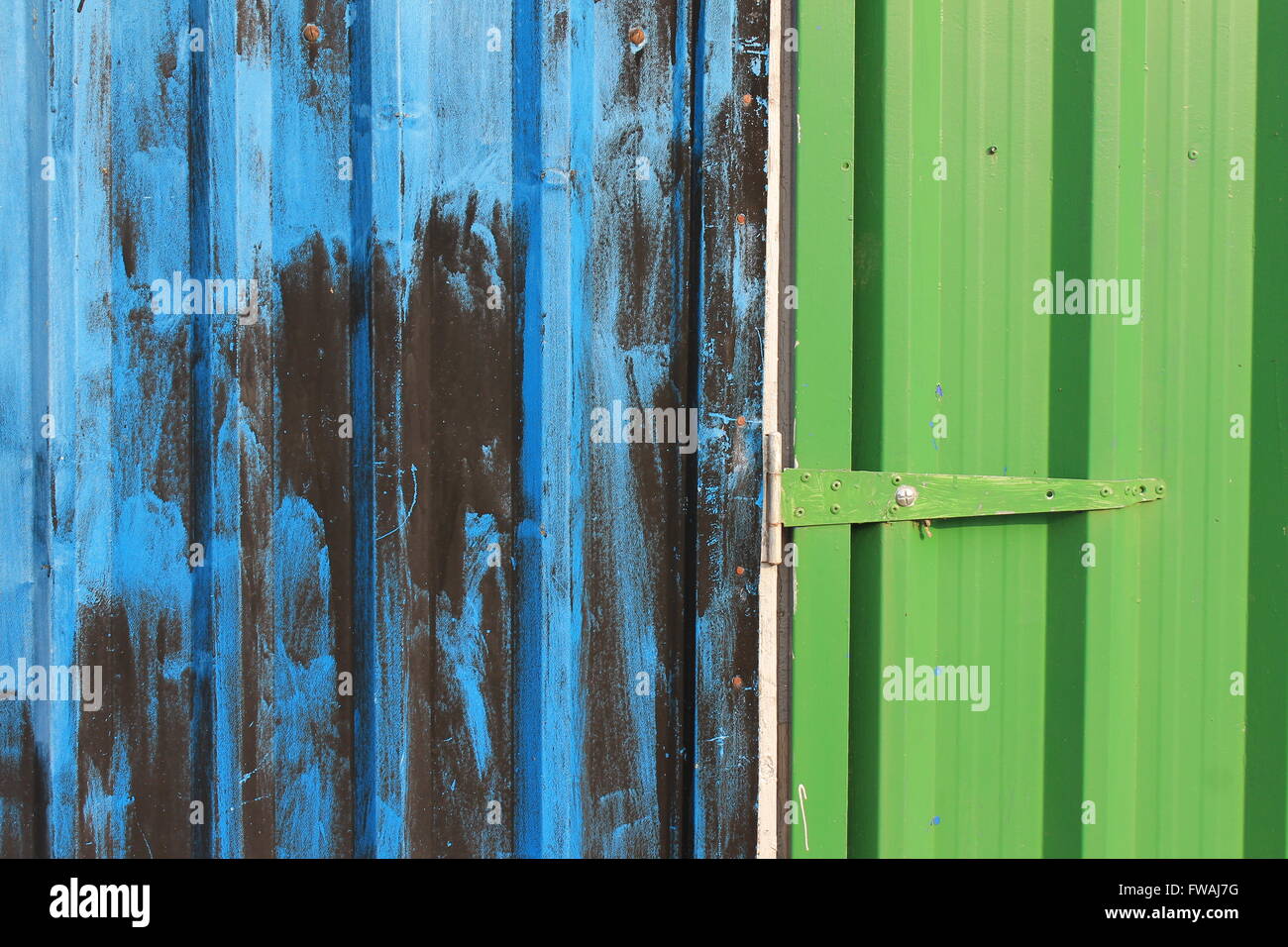 Blue, black and green - bright paintwork on old doorway make of corrugated sheet metal Stock Photo