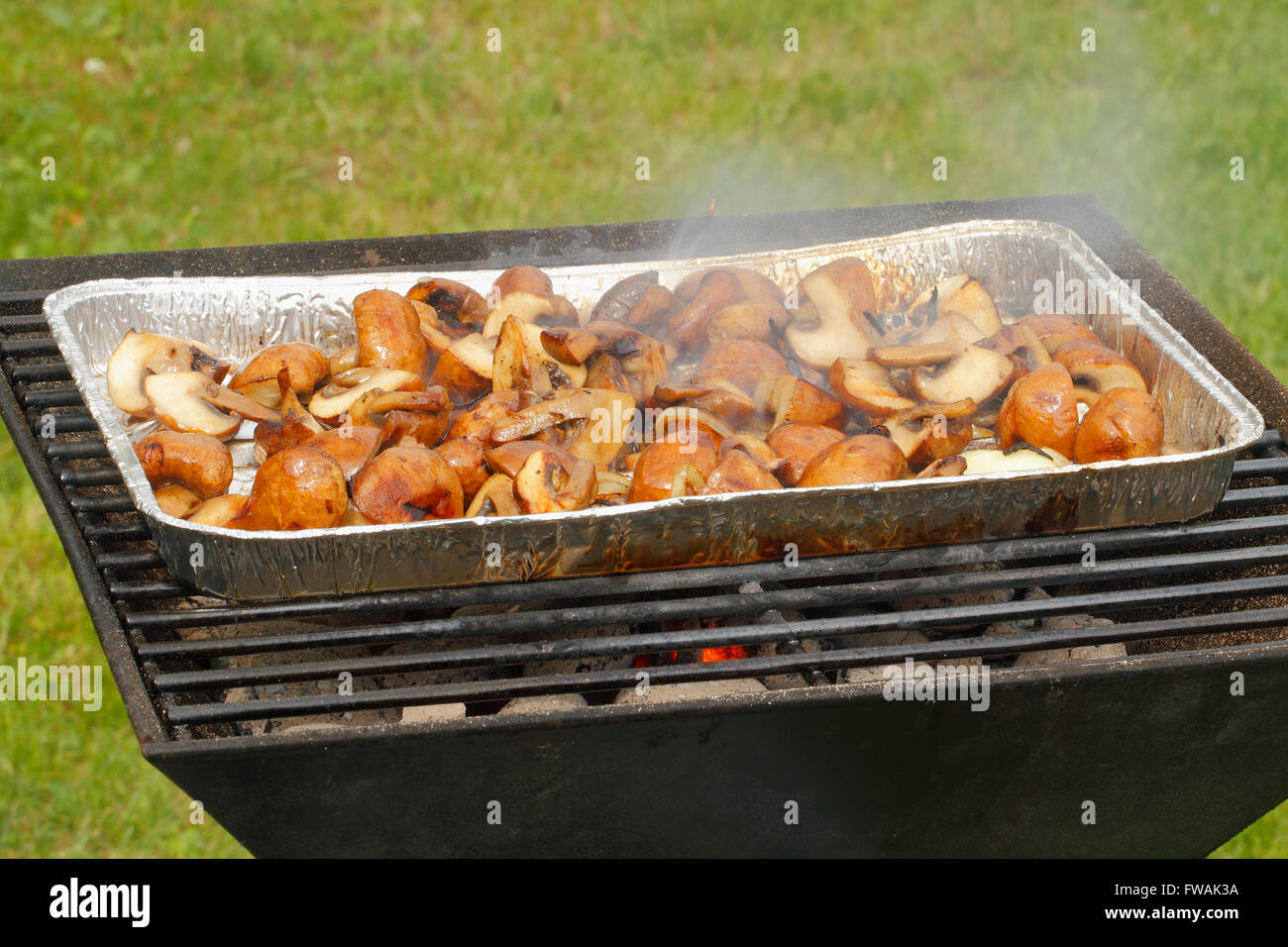 Grill with a grill pan, filled with mushrooms and onion rings Stock
