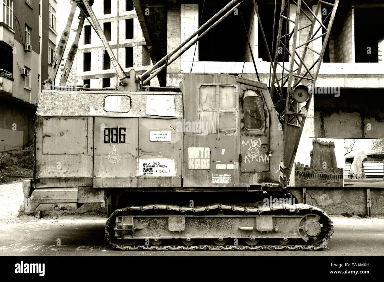 An ancient steel crane shown parked by a modern construction site in Baku, Azerbaijan Stock Photo