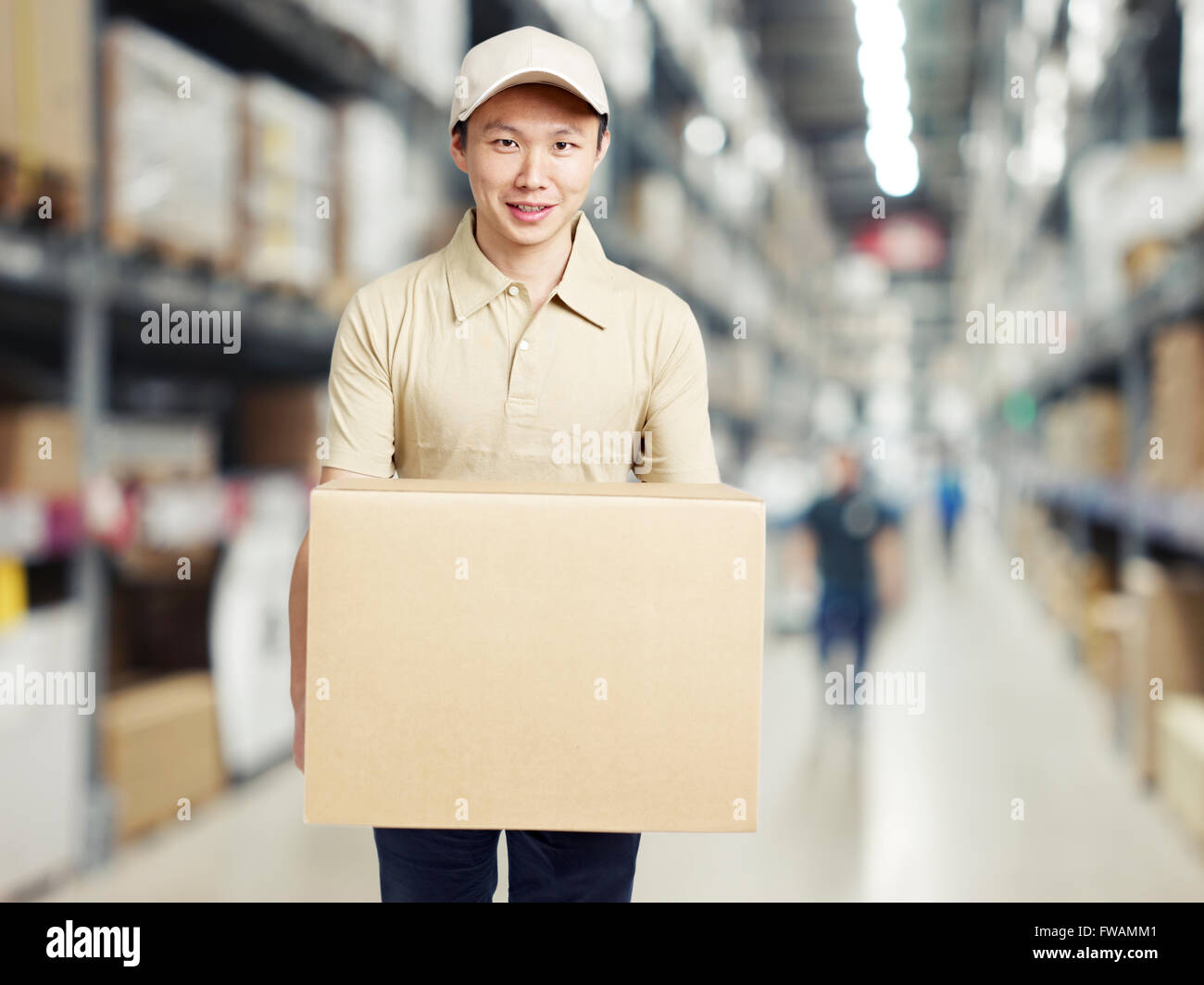 male warehouse worker carrying a carton box of goods Stock Photo