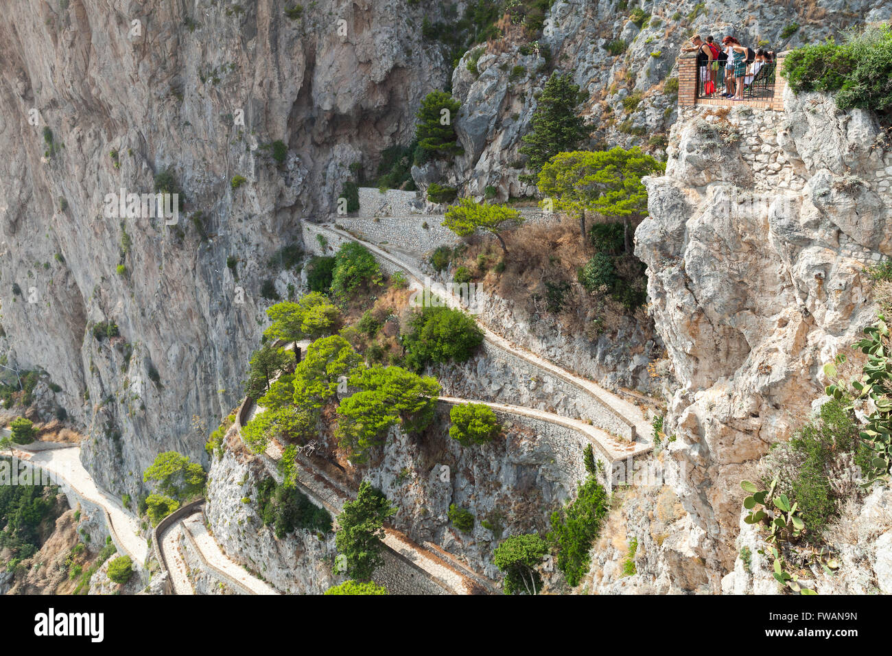 Capri, Italy - August 14, 2015: Tourists looks down on winding mountain road from high viewpoint of Capri island Stock Photo