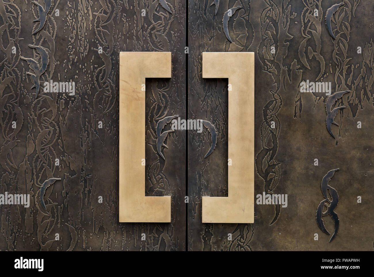 Brass doorhandles on a patterned bronze door on a London apartment Stock Photo