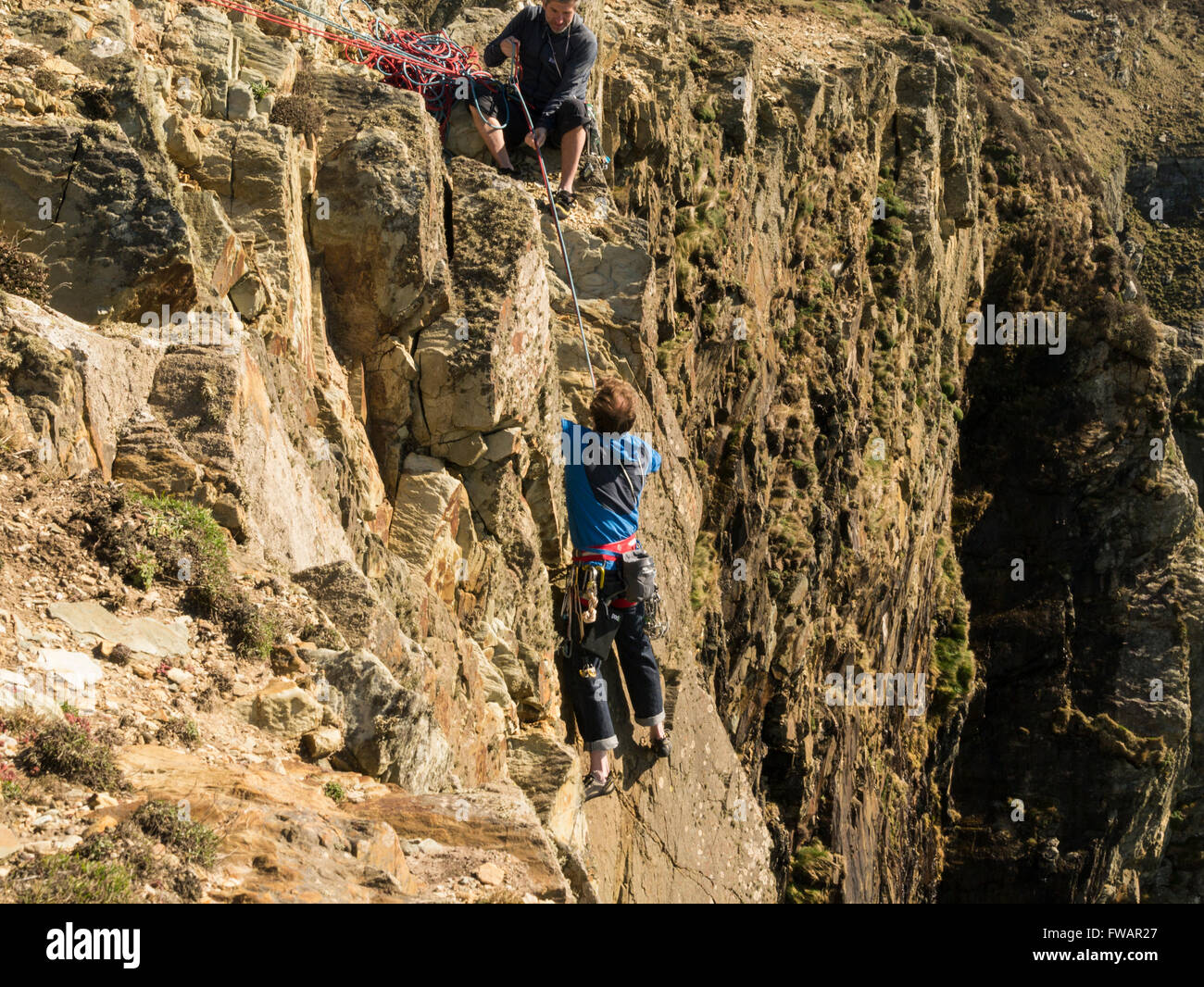 Young man reaching top rock climbing on South Stack Cliffs Isle of