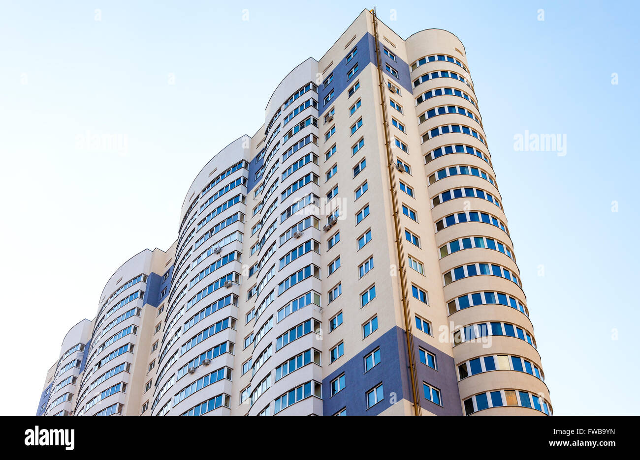 New tall apartment building against blue sky background Stock Photo - Alamy