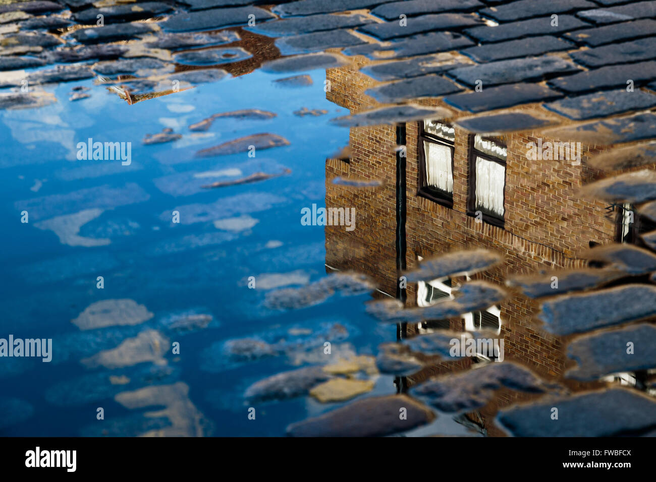 Cobblestone with reflection of house in puddle after rain Stock Photo ...