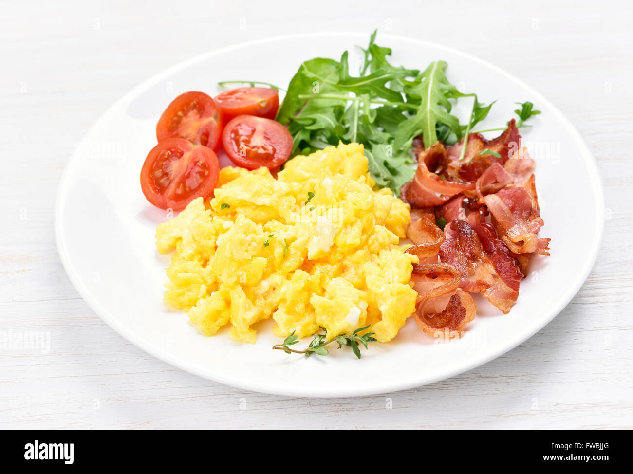 Plate with scrambled egg and bacon on white background Stock Photo - Alamy