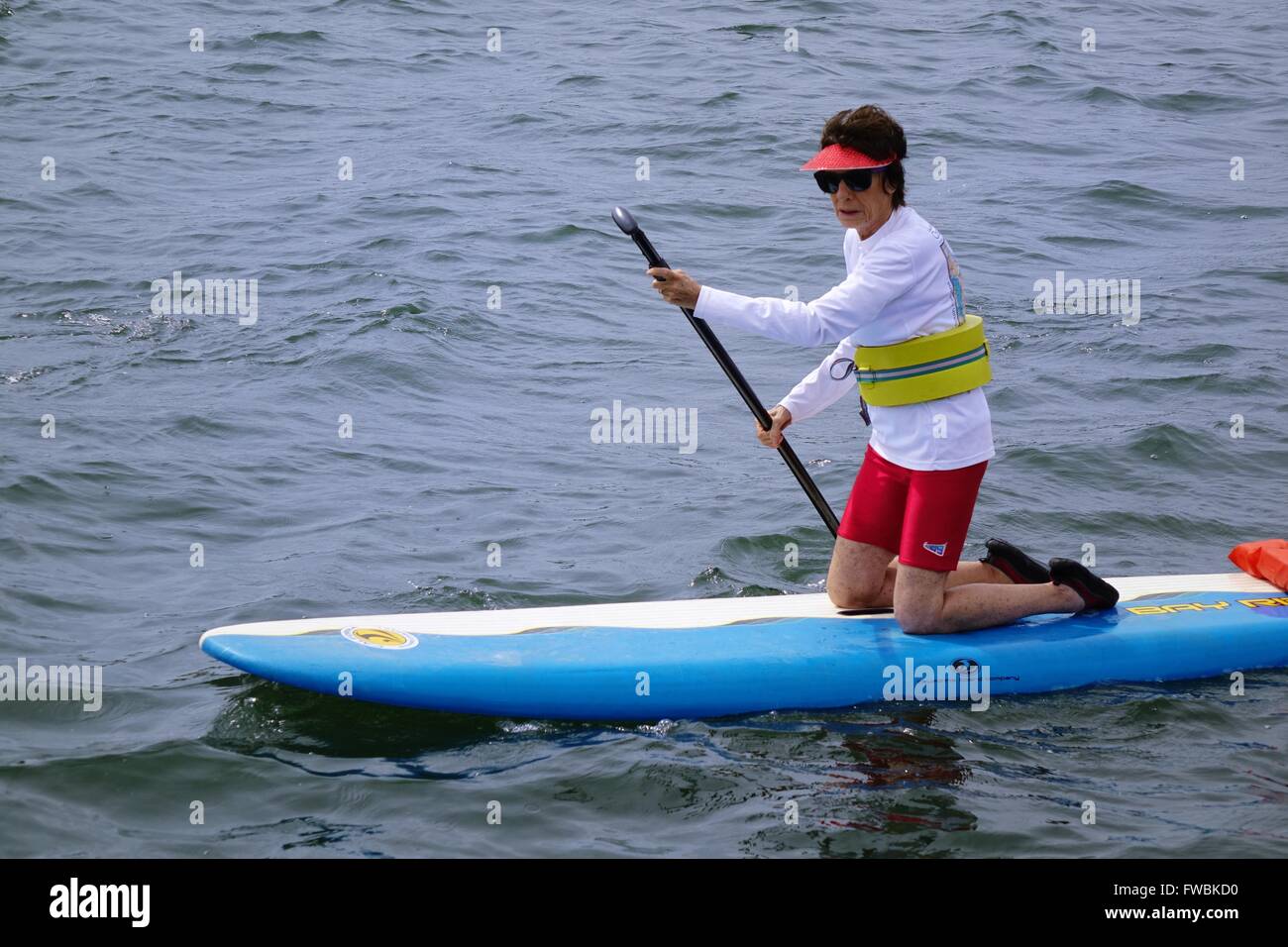 Paddleboarder on knees wearing flotation device on waist Stock Photo
