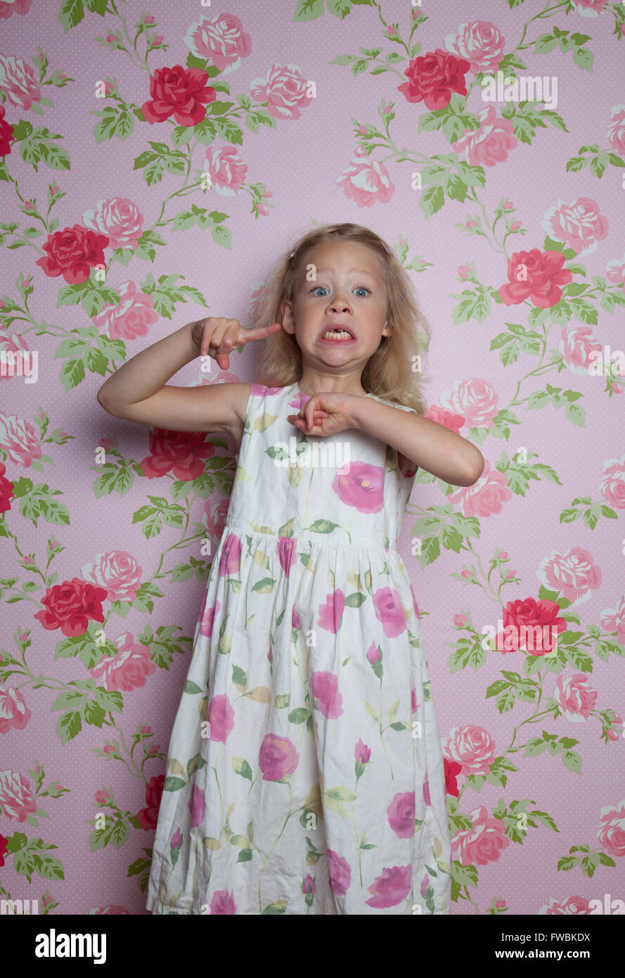Girl with a patterned wall paper pulling face Stock Photo