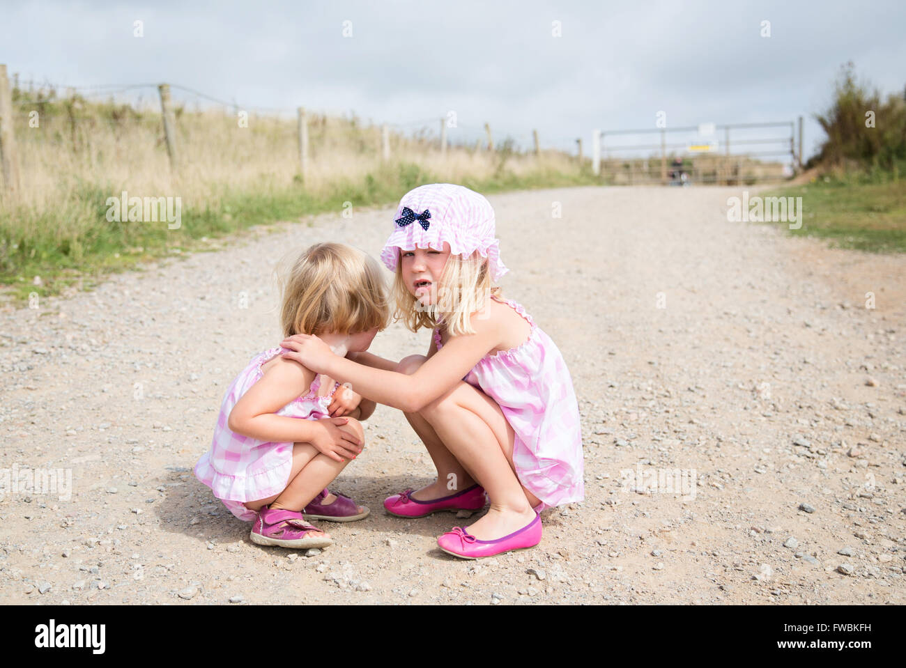 Two girls crouching one consoling Stock Photo