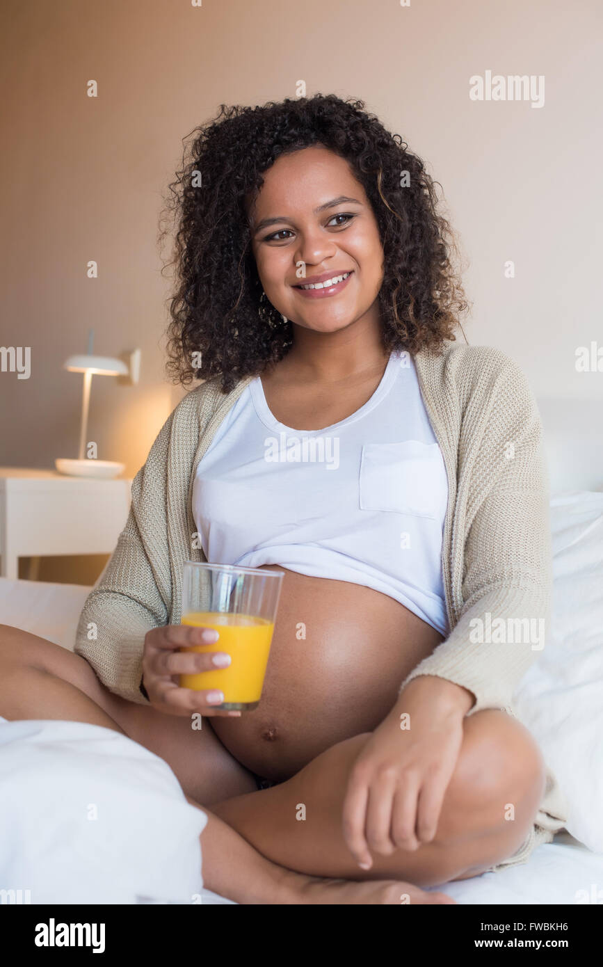 Pregnant woman drinking orange juice in bedroom Stock Photo - Alamy