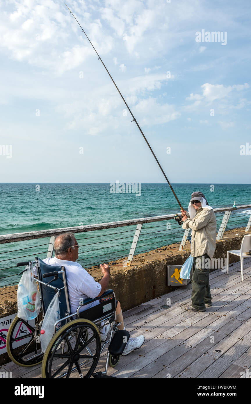 Man fishing on a promenade in Tel Aviv Port district in Tel Aviv city, Israel Stock Photo