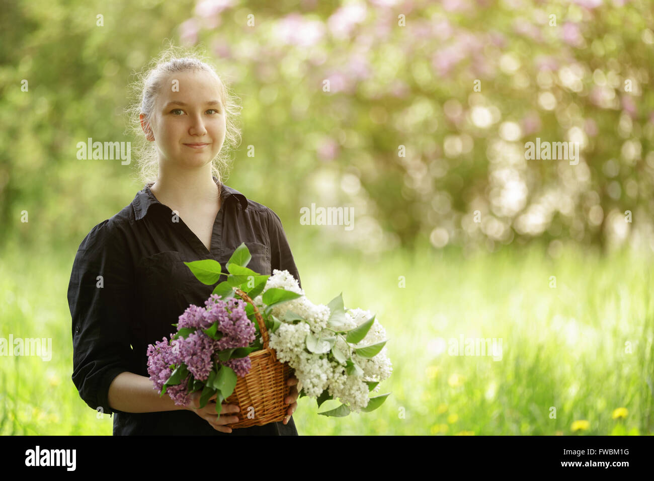 female teen girl hold basket full of lilac flowers Stock Photo