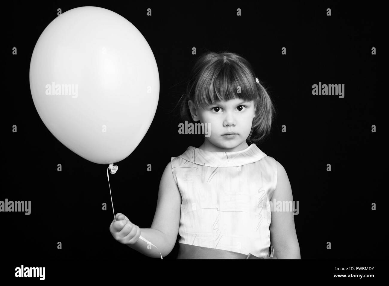 Portrait of serious Caucasian blond little girl with white balloon Stock Photo