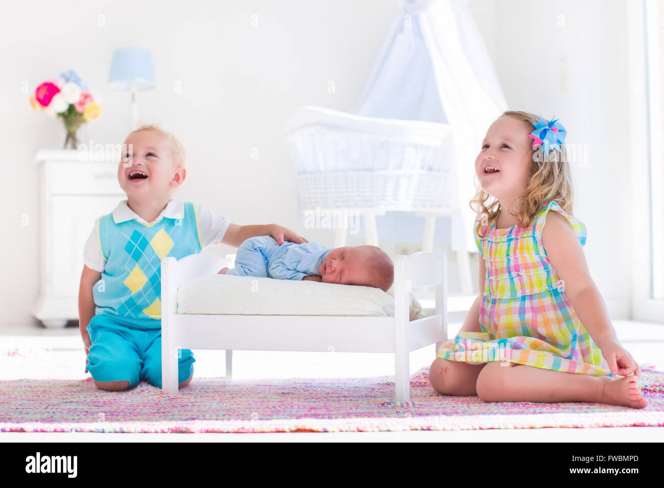 Cute little boy and girl kissing newborn brother. Toddler kids meet new