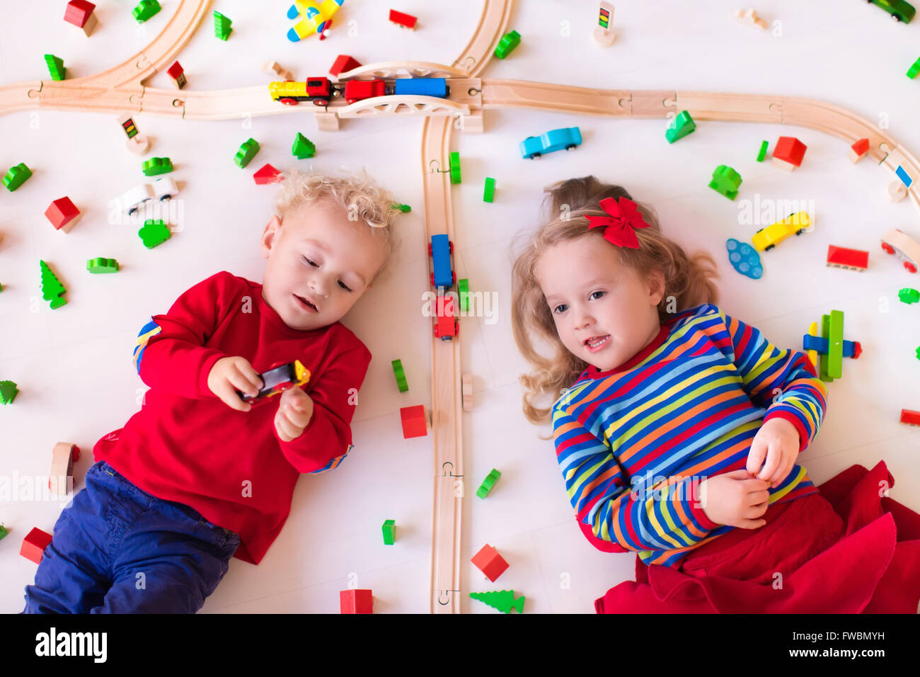 Children playing with wooden train. Toy railroad. Toddler kid and baby
