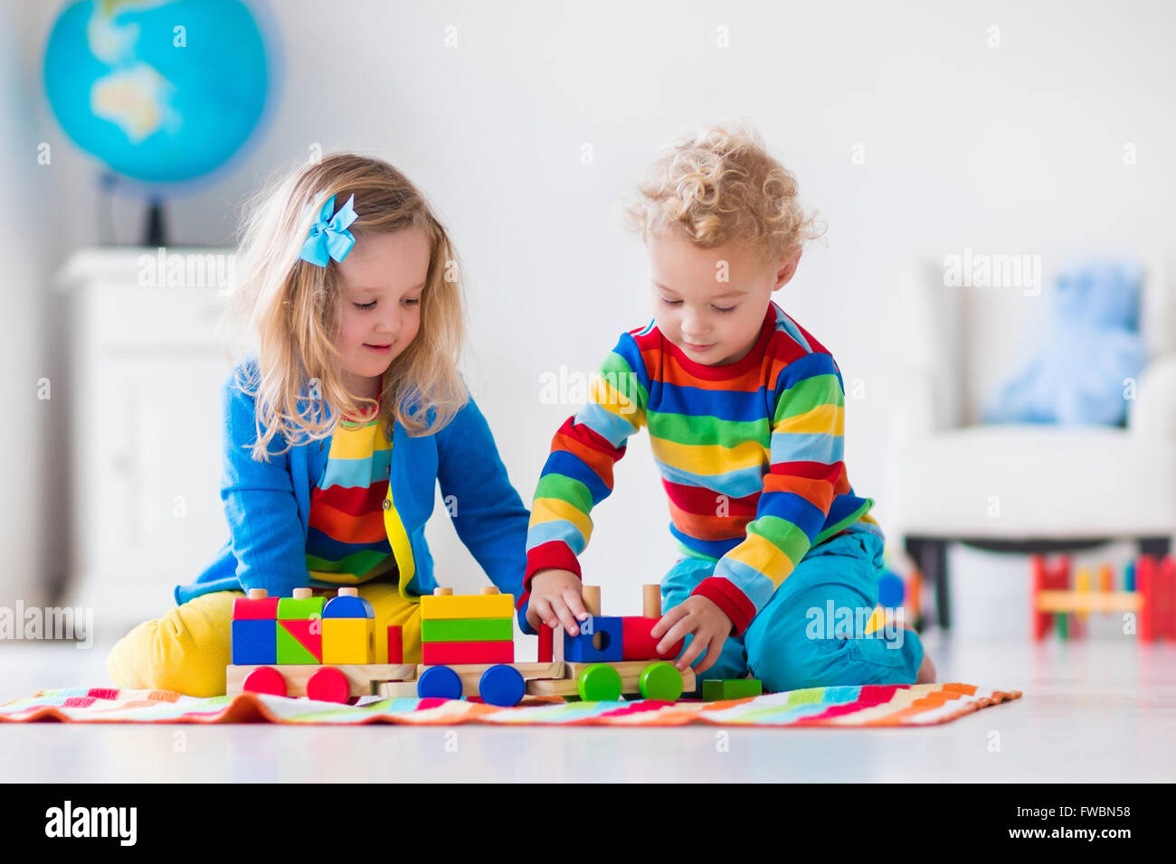 Children playing with wooden train. Toddler kid and baby play with