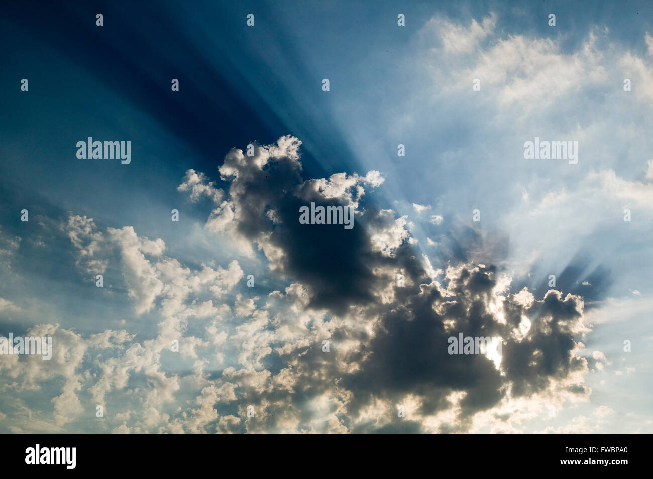 Large clouds block out the sun sending huge rays of light spilling out from around the edges. Stock Photo