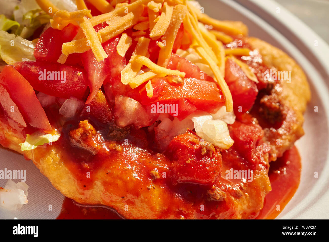 Modern Native American cooking; a piece of frybread covered with chili, lettuce, tomato and cheese shreds, an Indian Taco Stock Photo