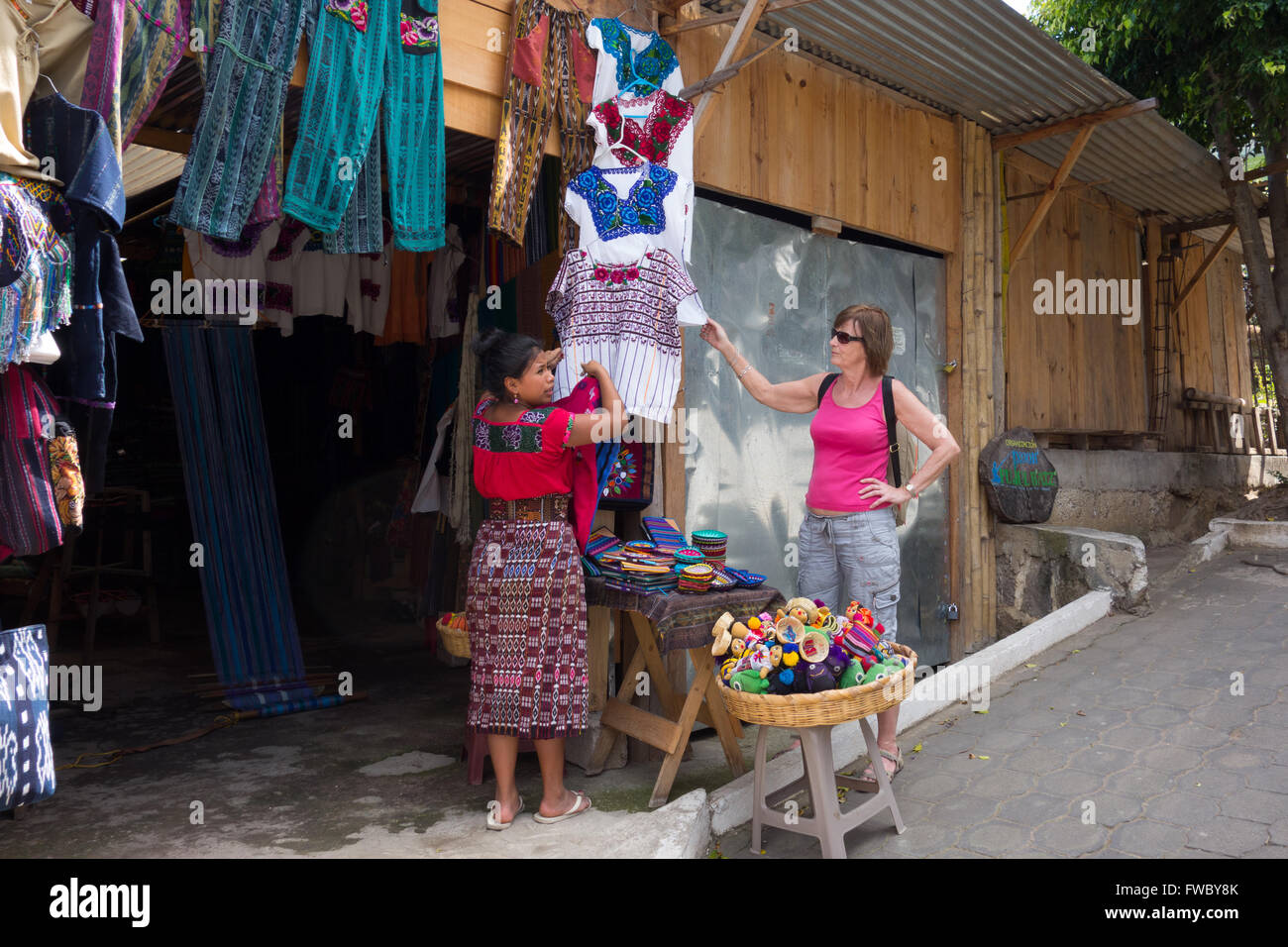 Tourist buying clothes at womens' cooperative shop in San Juan, Lake Atitlan Guatemala. Stock Photo