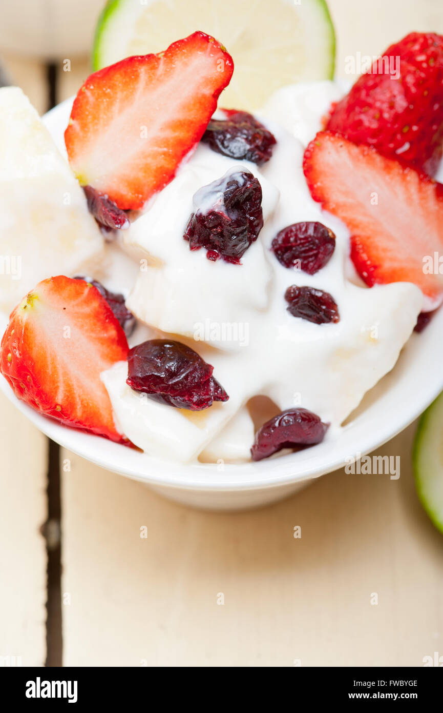 fruit and yogurt salad healthy breakfast over white wood table Stock
