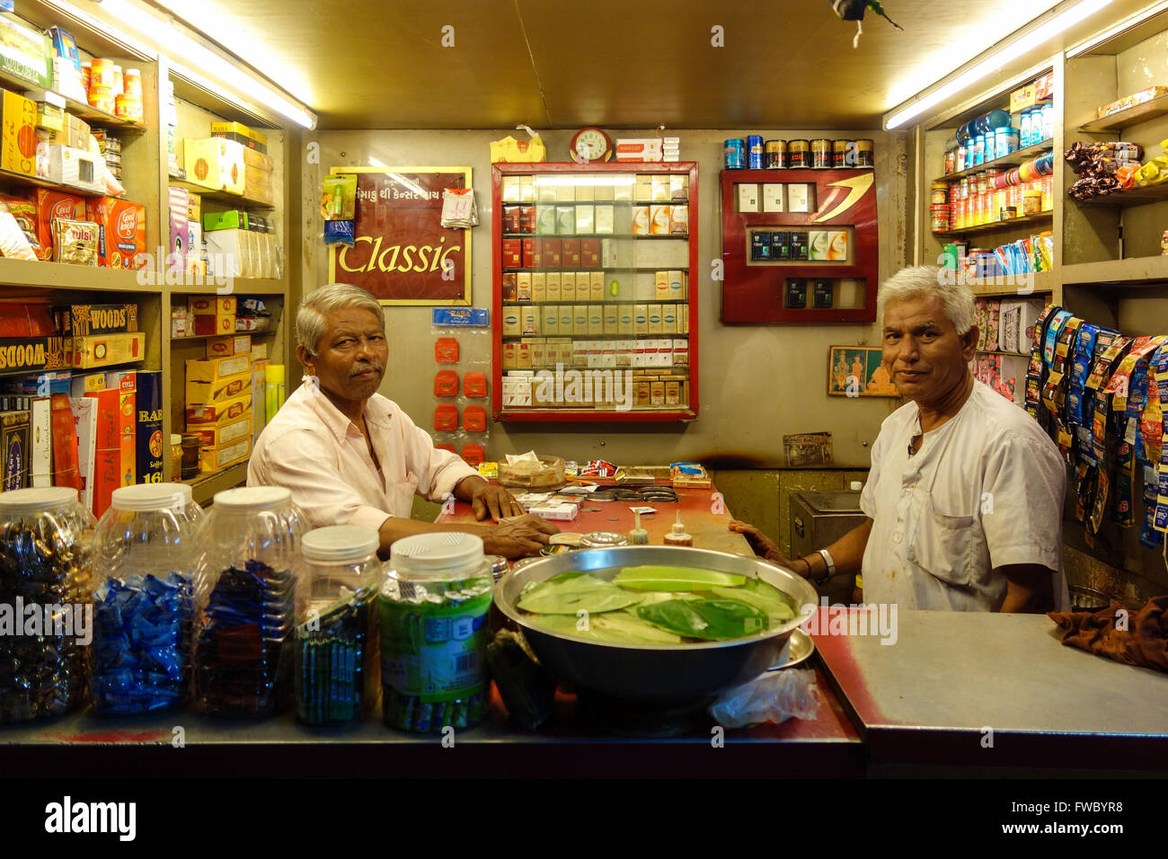 Two elderly Indian shopkeepers pose inside their shop selling tobacco products in Vadodara, Gujarat, India. Stock Photo