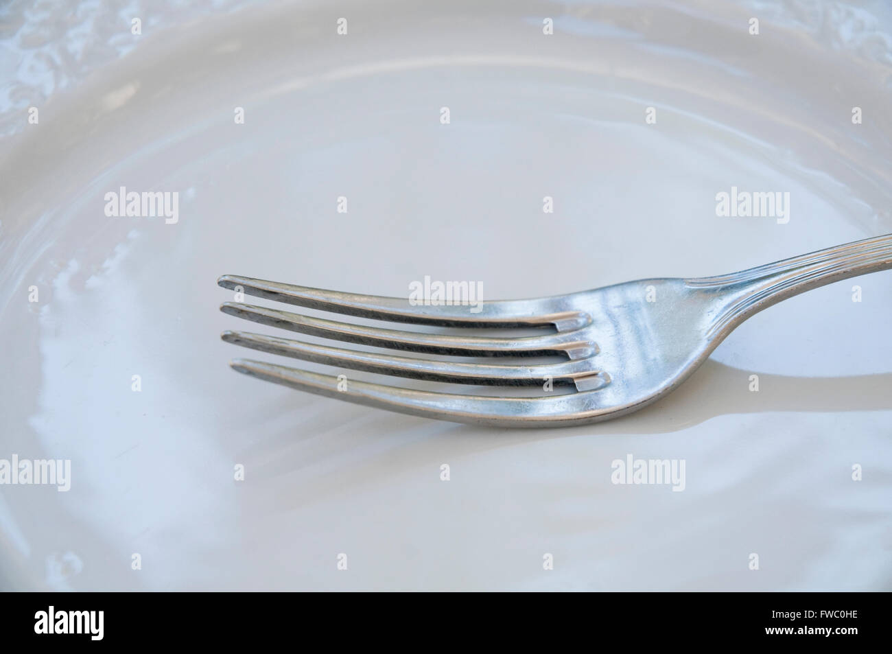 Fork on empty dish. Close view. Stock Photo