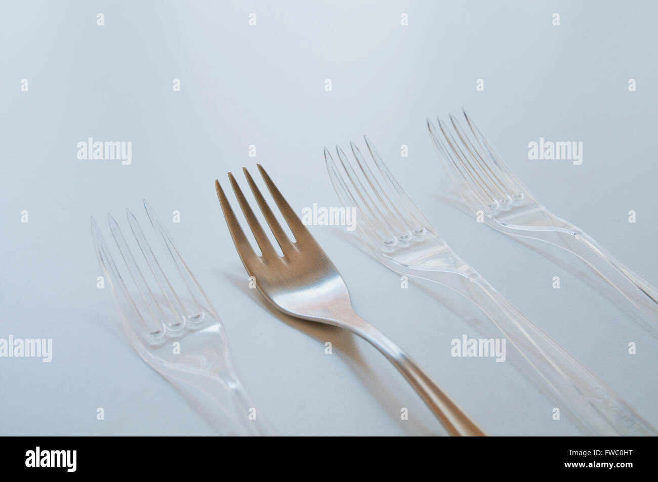 One metal fork and three plastic ones. Close view. Stock Photo
