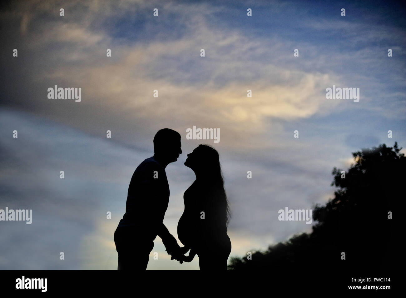 A young man and his pregnant wife at sunset. silhouettes Stock Photo ...