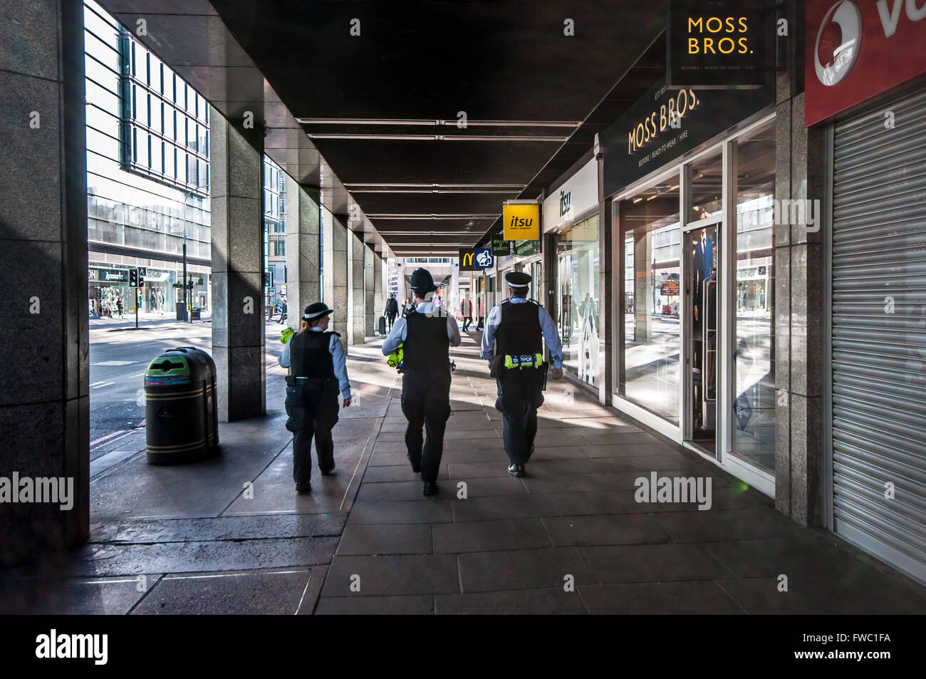 Three policemen on the beat in London, UK. Walking past shop windows. Male. Female Stock Photo