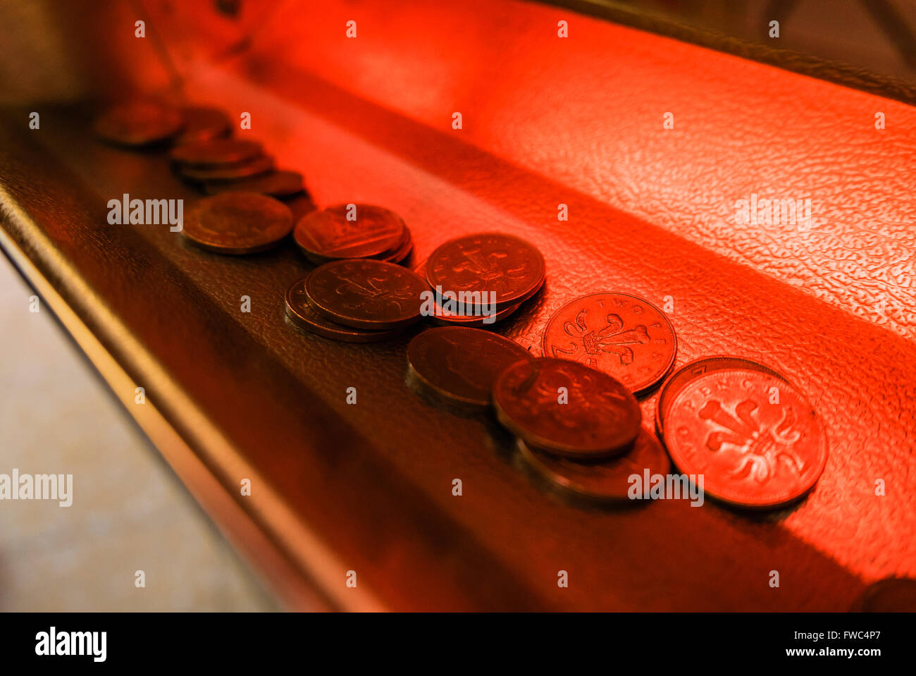 Two pence 2p pieces coins in the tray below a tuppeny nudger machine at a British seaside funfair. Stock Photo