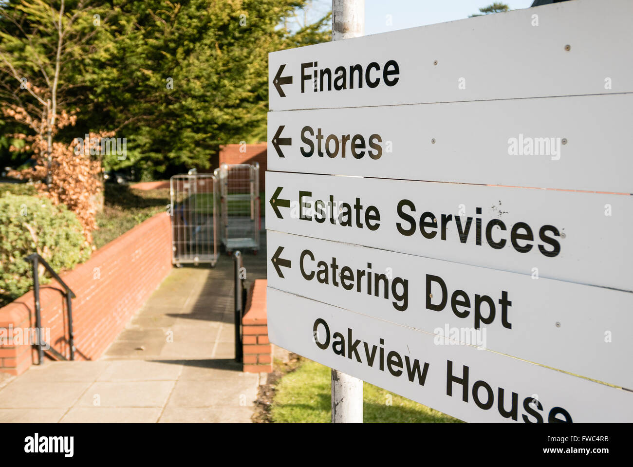 Sign at a hospital giving directions to various administration and service units Finance, Stores, Estate Services, Catering Depa Stock Photo