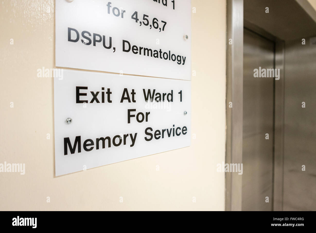 Sign at a lift in a hospital advising patients to exit at Ward 1 for the memory service. Stock Photo
