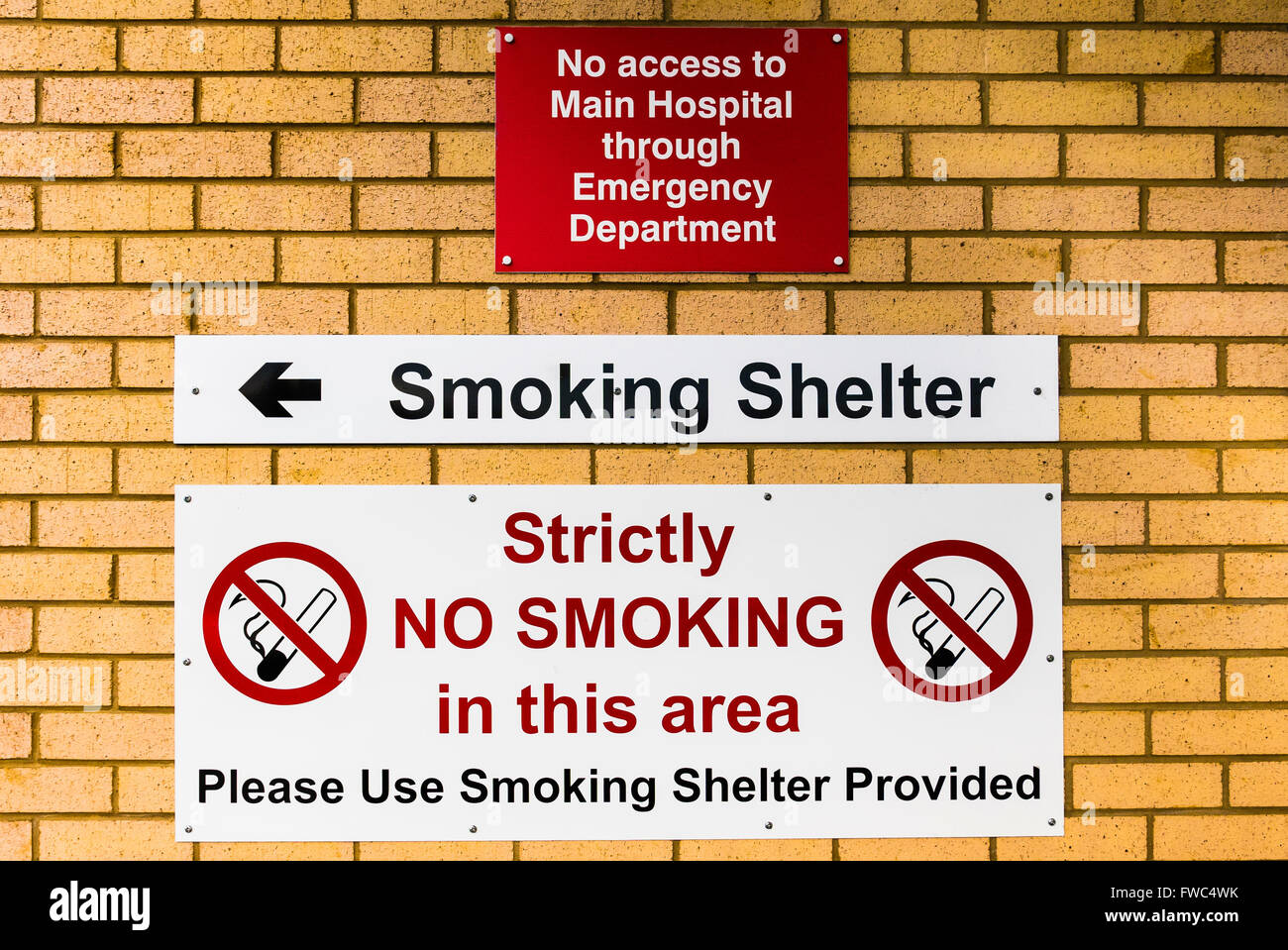 Signs at the entrance of a hospital emergency department, warning tha no access to the main hospital is possible, and smoking is Stock Photo