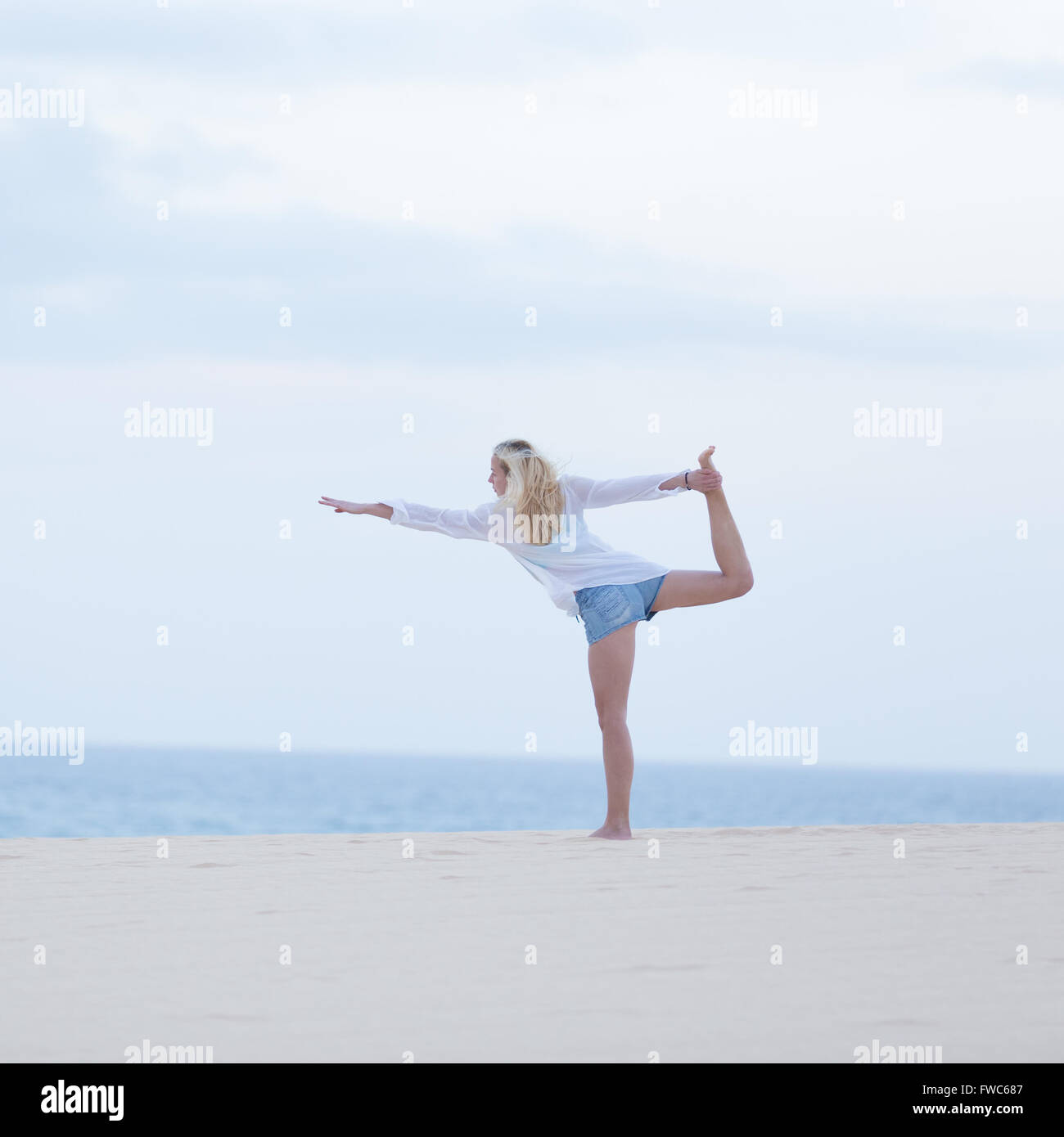 Free woman streching on beach at down. Stock Photo