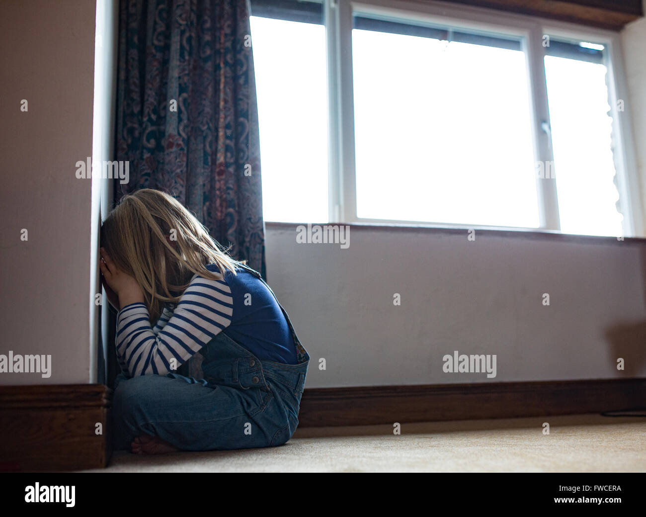 A 7-year-old girl faces the wall as a punishment for being naughty Stock Photo