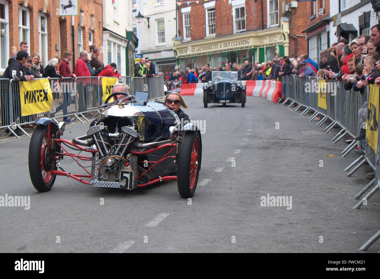 Bromyard Herefordshire April 2016 - the inaugural Speed Festival through the streets of Bromyard the birthplace of the Morgan Motoring Company. Shown here driving through the town is a 1933 Morgan Super Sports three wheeler vintage car. Stock Photo