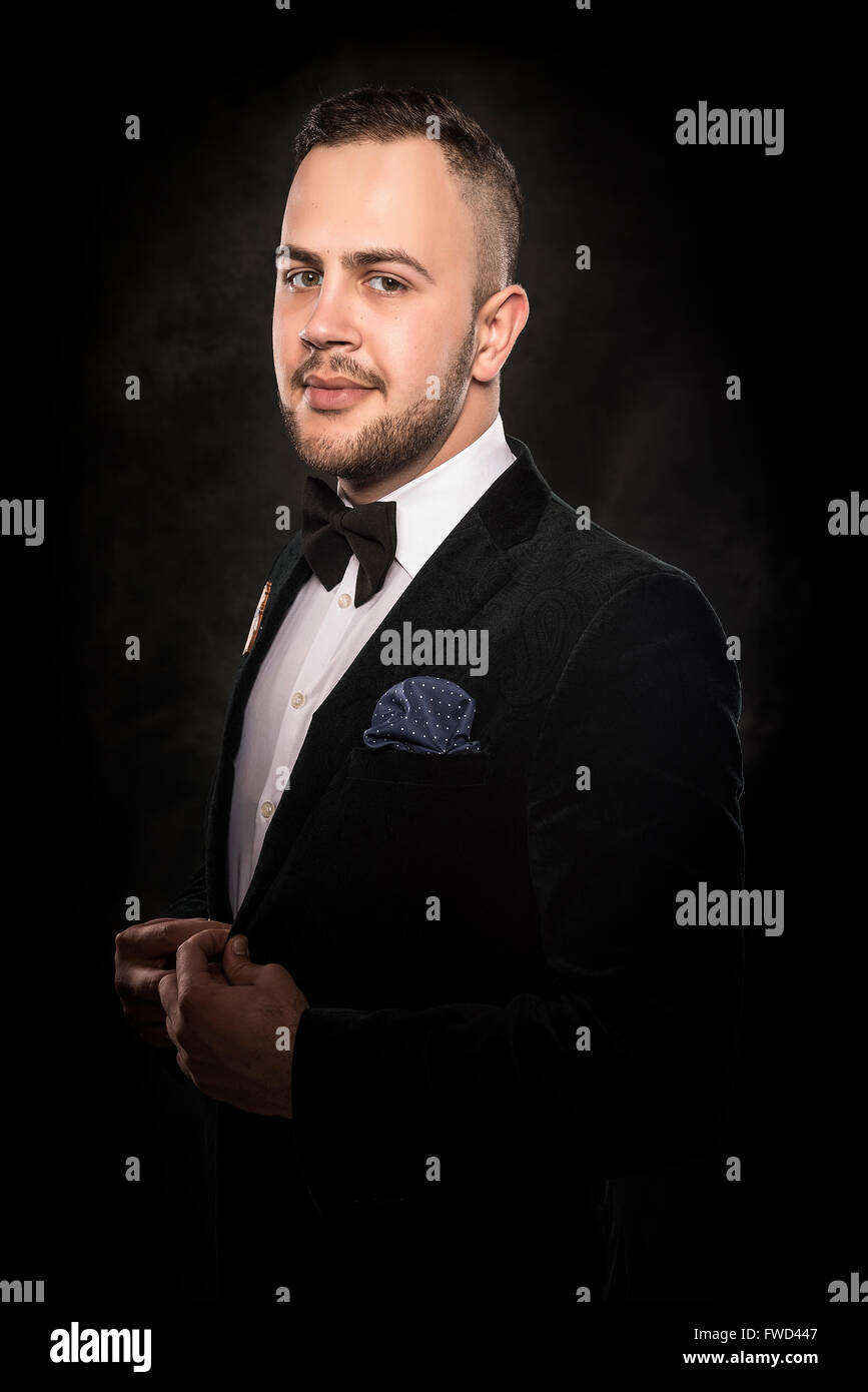 Young handsome man in black suit on dark background Stock Photo - Alamy