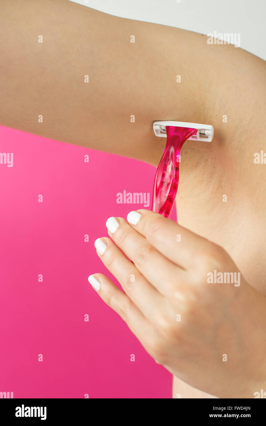 woman shaving her armpit with red shaver Stock Photo