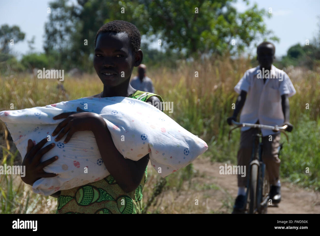 Lacekocot, Pader, Uganda.  Acholi  man and woman at the Lacekocot IDP Camp go about their business. The man is on a bicycle. Stock Photo